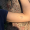 Person with 'Still I Rise' temporary tattoo on arm against a tree background