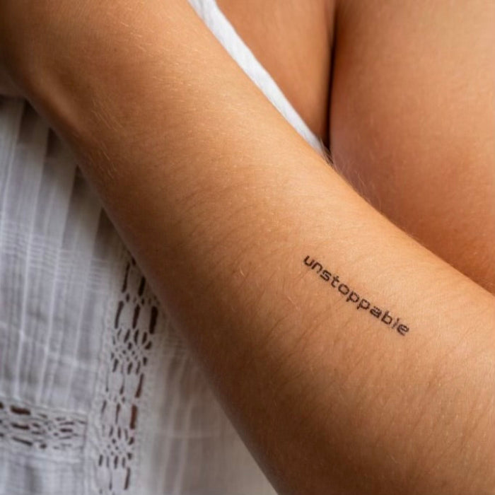 Unstoppable motivational temporary tattoo in modern font on arm symbolizing drive and determination.