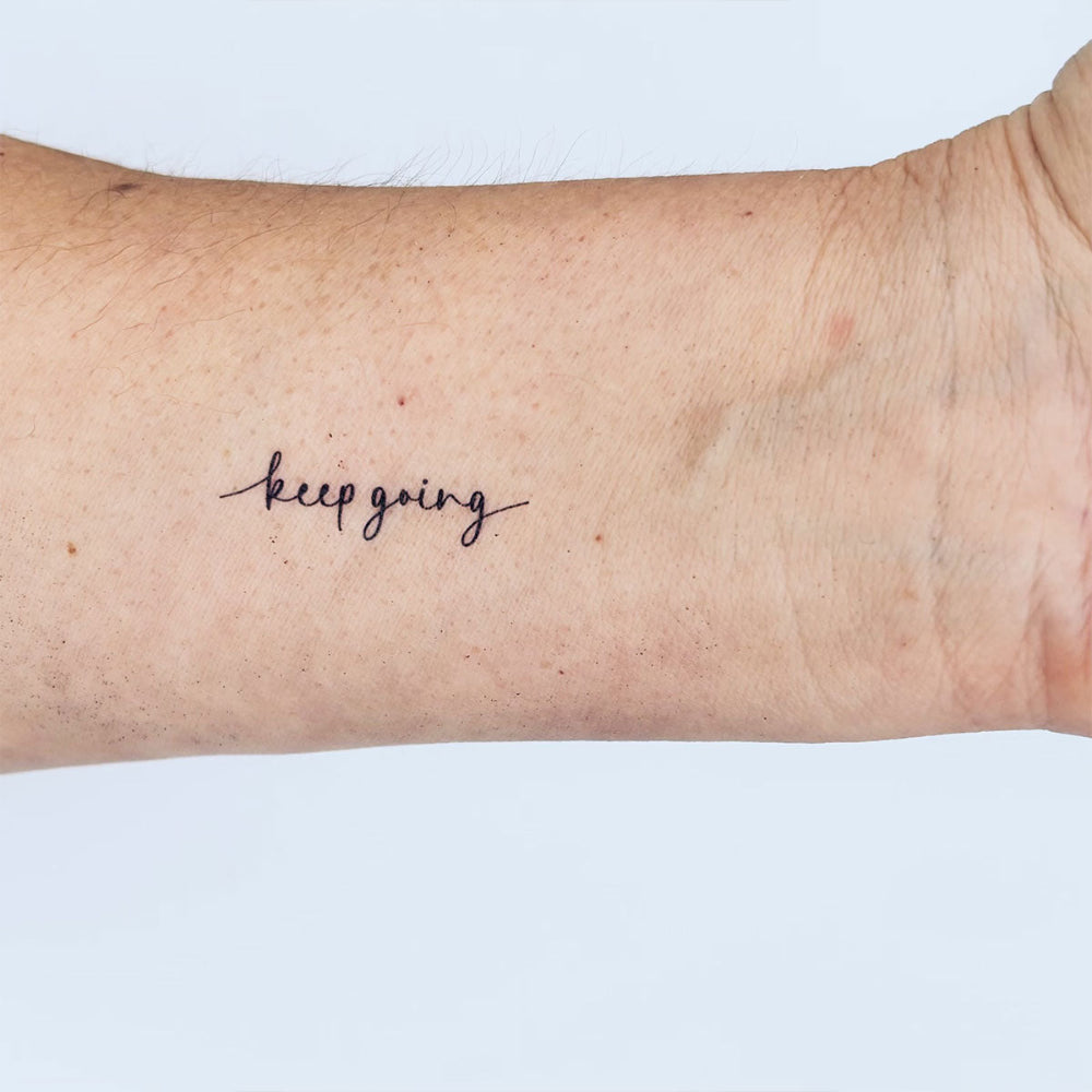 'keep going' motivational temporary tattoo by MotivInk – inner forearm black ink reminder for perseverance and strength.