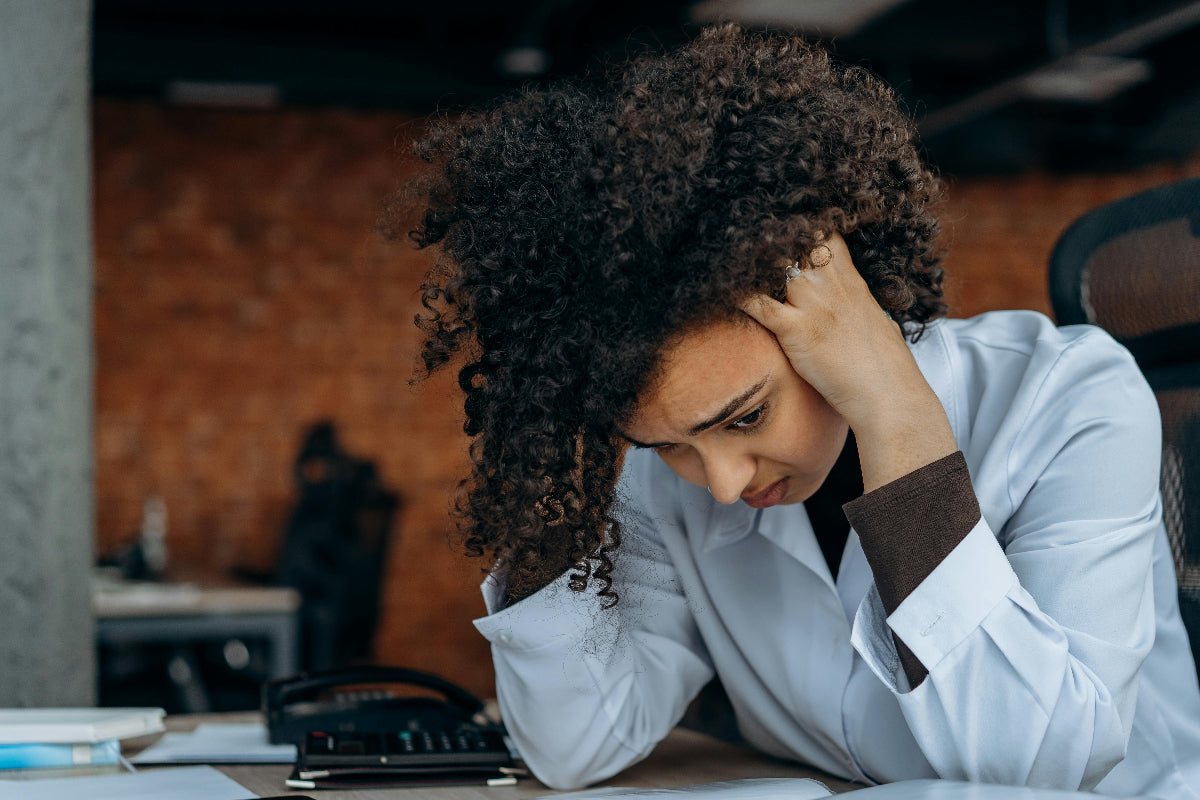 Person in a blue shirt sitting at a desk with a concerned expression.