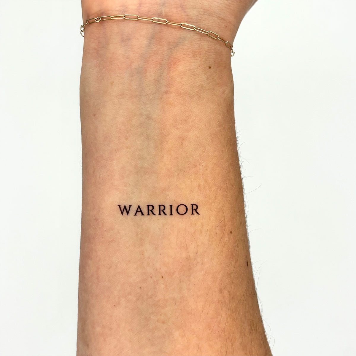 'WARRIOR' - Clean black lettering tattoo placed on inner forearm – motivational temporary tattoo for strength and grit.