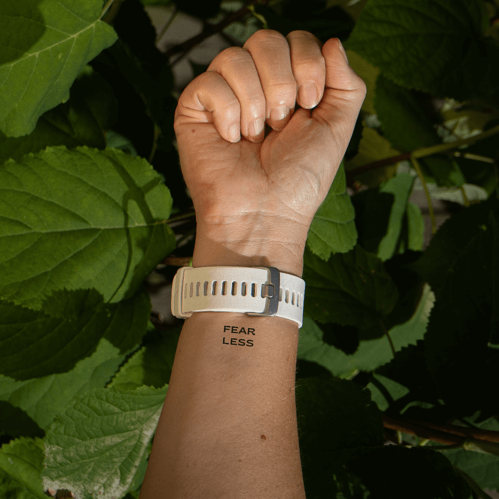 'FEAR LESS' empowering quote tattoo by MotivInk – inner arm placement for confidence and courage