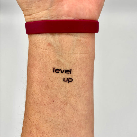 'level up' motivational temporary tattoo – inner forearm black ink quote for self-improvement and progress, contemporary ink by MotivInk